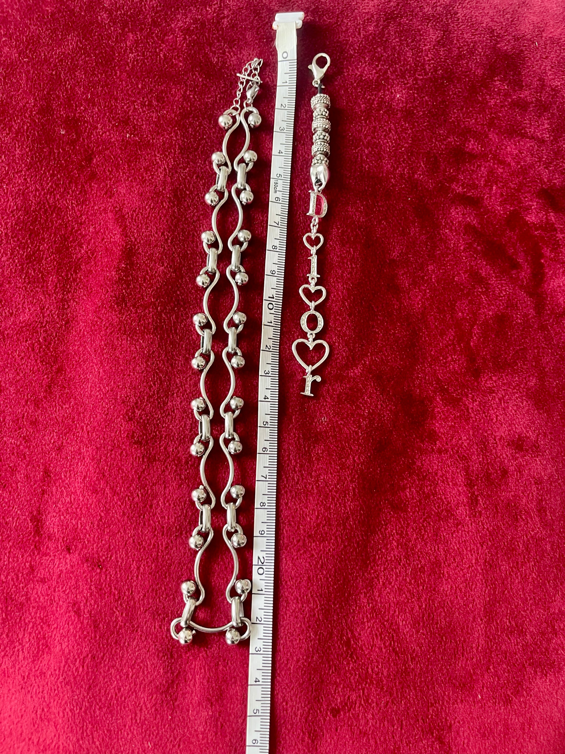  Dior phone charm pendant with silver beads and clasp detail, highlighting one-of-a-kind design using measuring tape on red background .