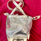 Full view of Paco Rabanne silver shoulder/wrist bag with both straps shown, on red velvet fabric background.