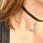 Side view of Person wearing a black leather Yves Saint Laurent choker necklace with a heart-shaped pendant and logo charm YSL