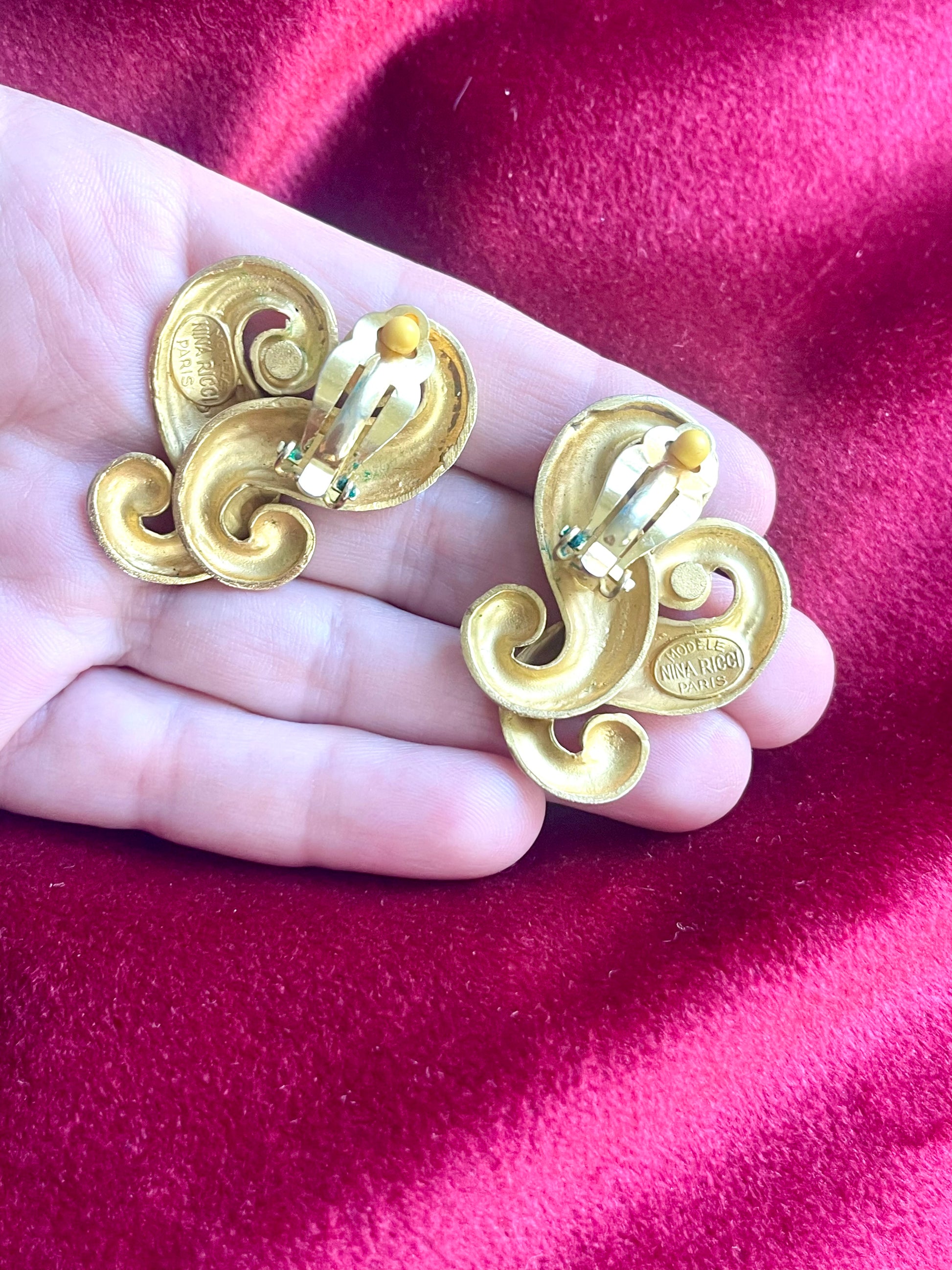 Displayed on hand Back view of signed Nina Ricci Paris earrings in matte gold plated metal, minor signs of wear visible
