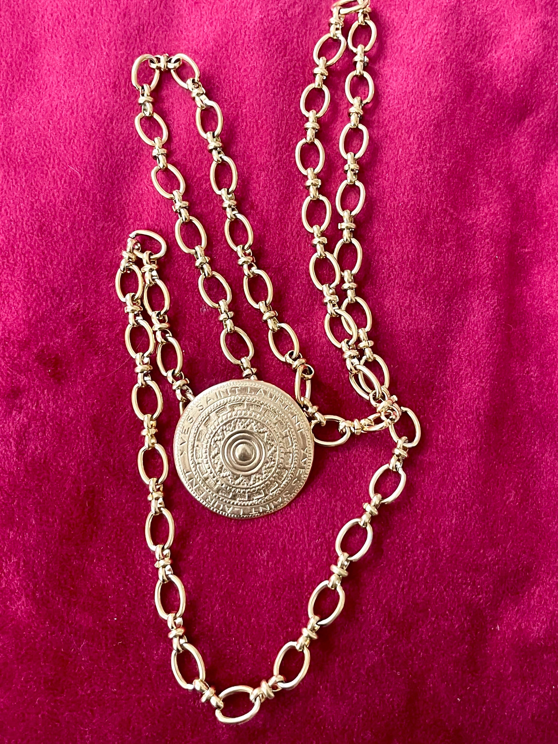 Top view Yves Saint Laurent vintage scarf holder Gold chain necklace on red fabric 