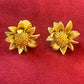 Orena Paris vintage gold sunflower-shaped earrings on a red background