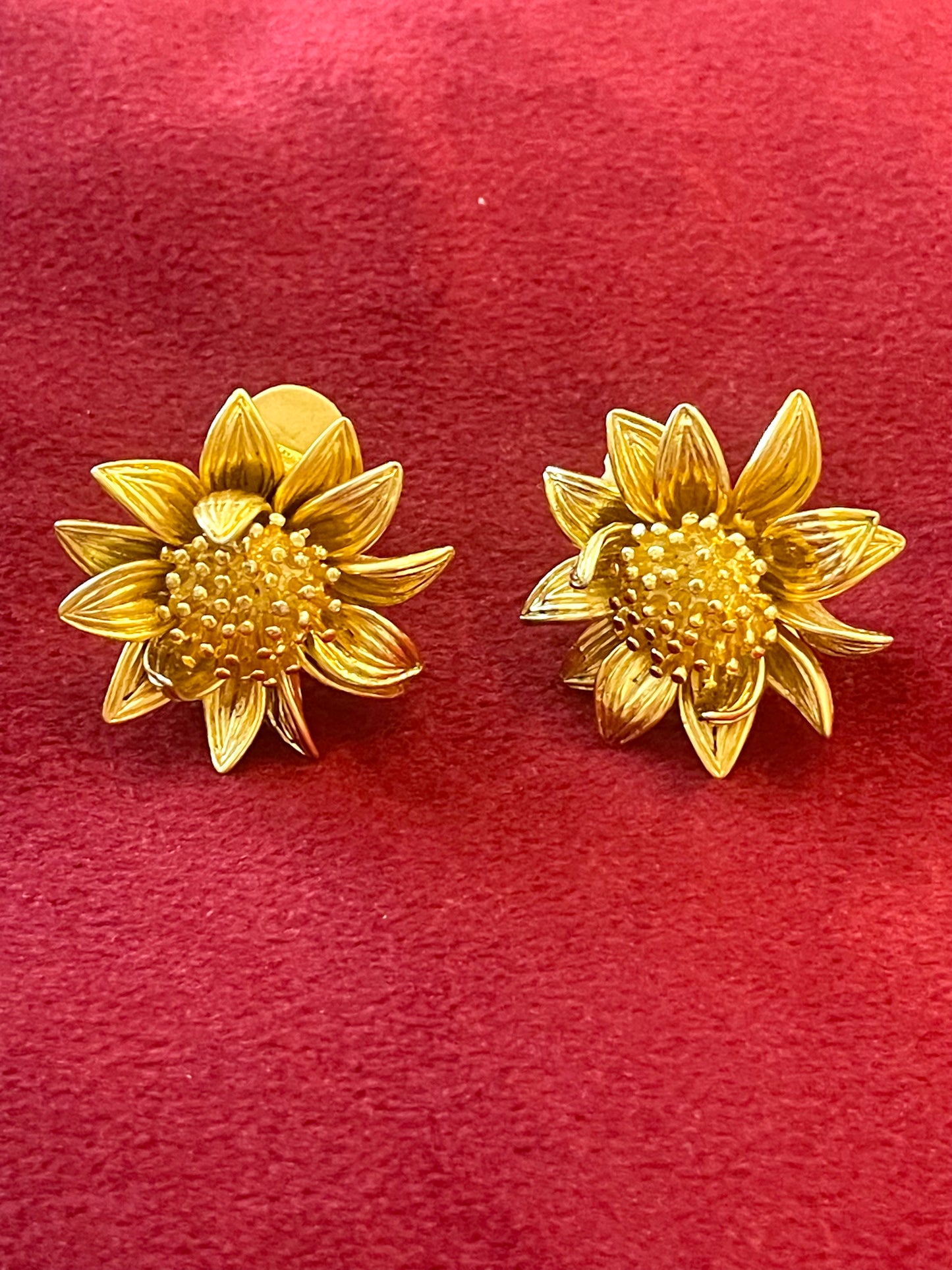 Orena Paris vintage gold sunflower-shaped earrings on a red background
