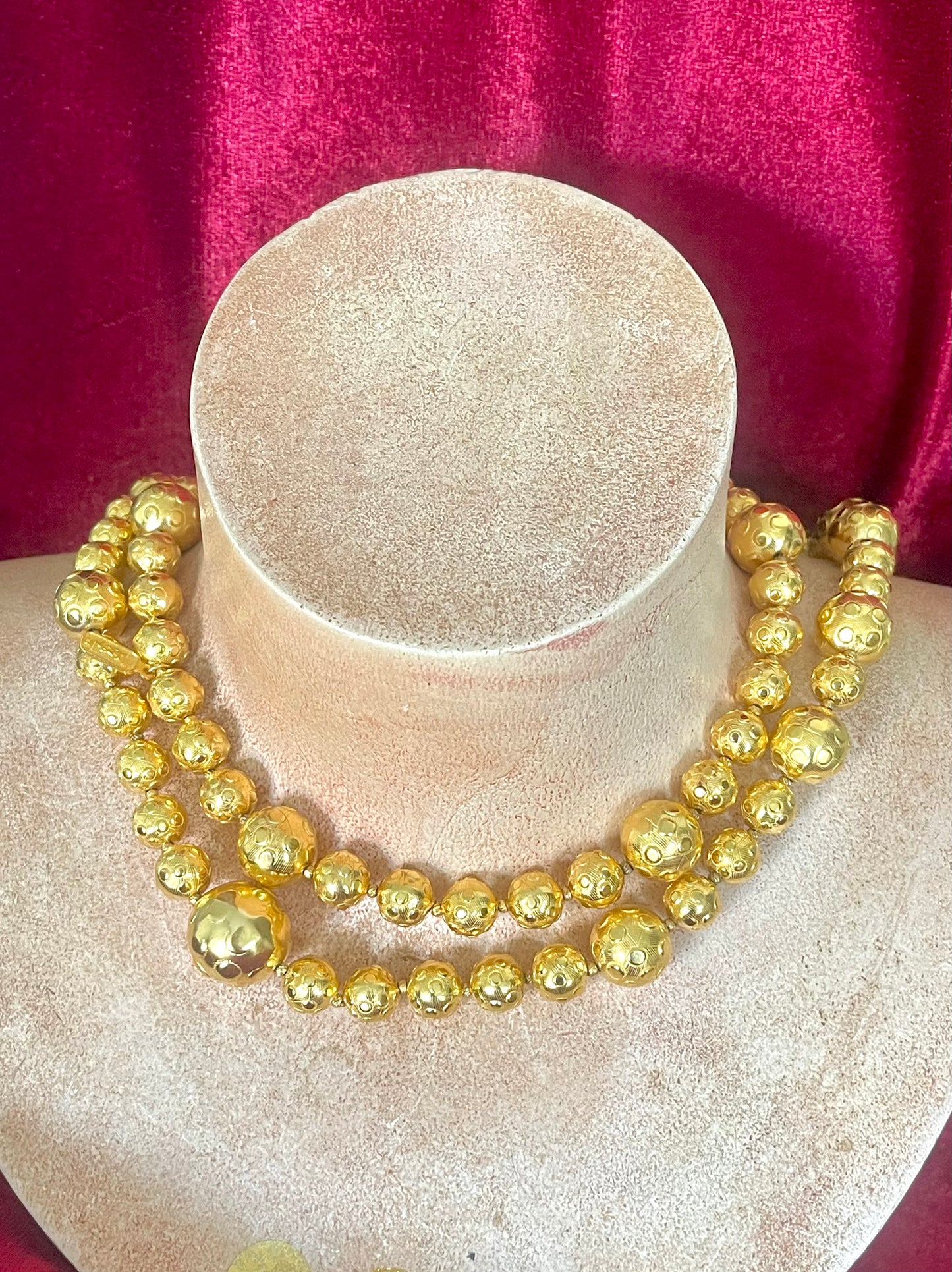 Gold beaded vintage Yves Saint Laurent necklace refurbished 18KG on a mannequin bust against a red fabric background
