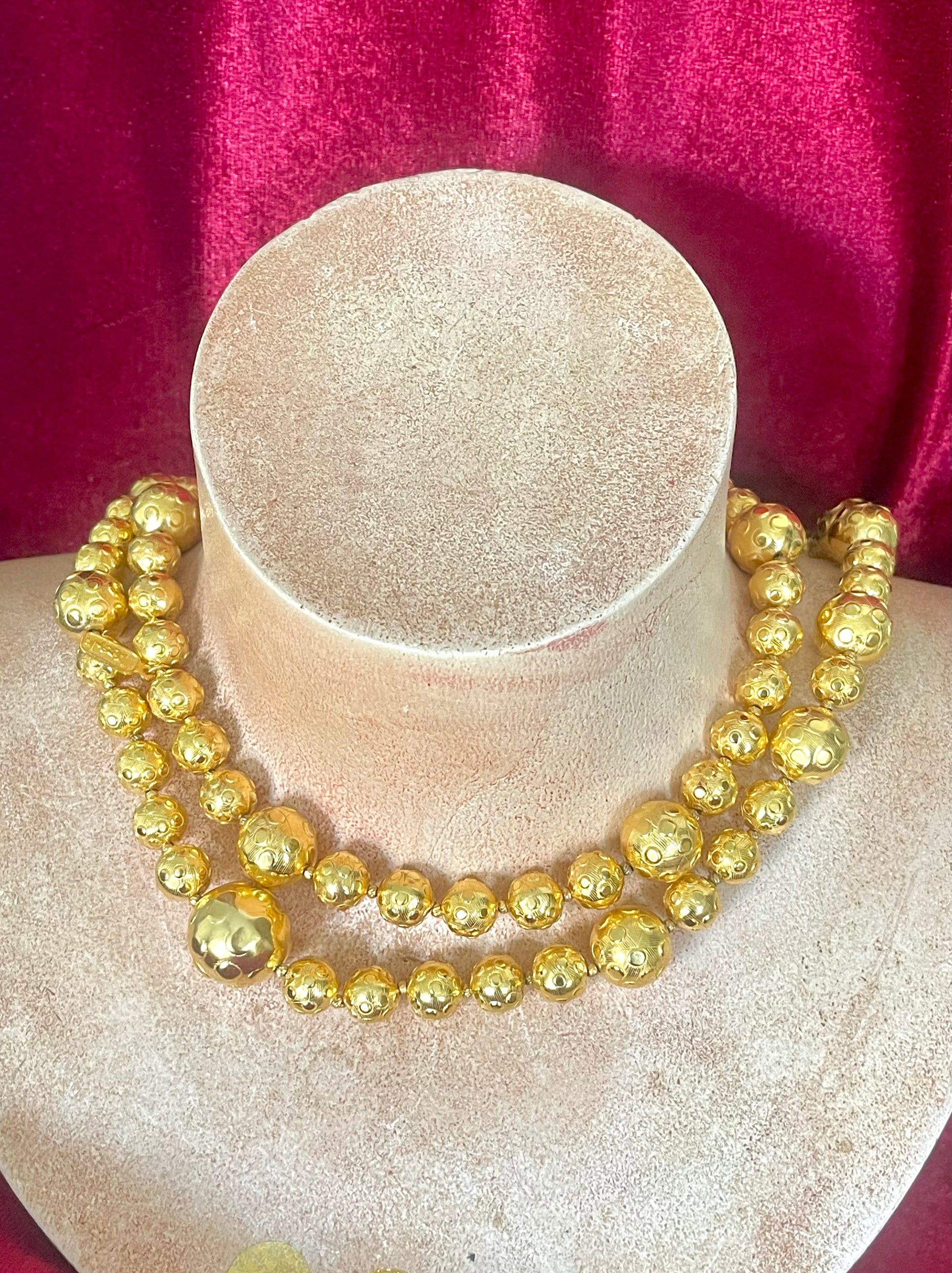 Gold beaded vintage Yves Saint Laurent necklace refurbished 18KG on a mannequin bust against a red fabric background