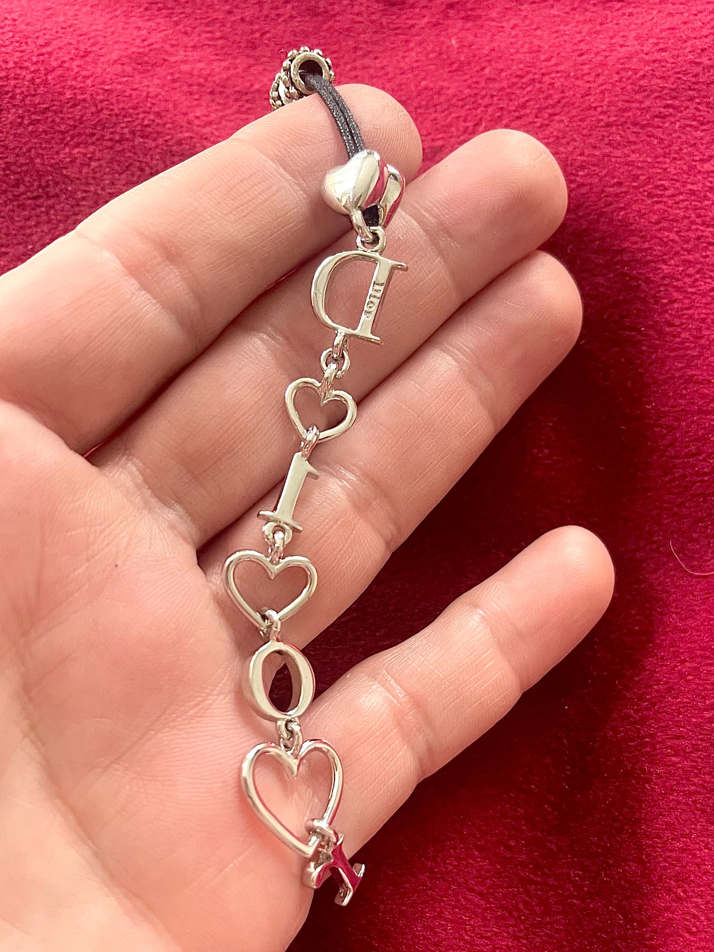 Back side view showing signature of Dior phone charm pendant on a red background 