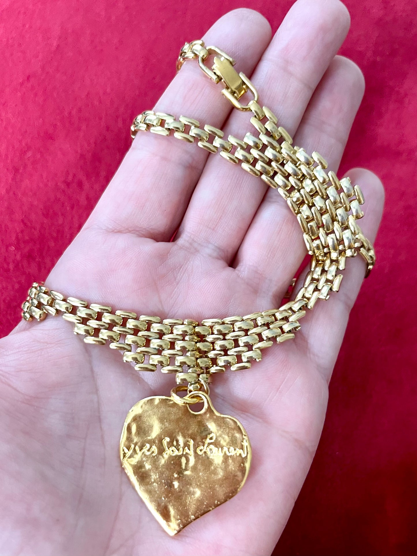Back side view of Vintage Refurbished 18KG Yves Saint Laurent 80s Love pendant Monet gold necklace , displayed on hand 