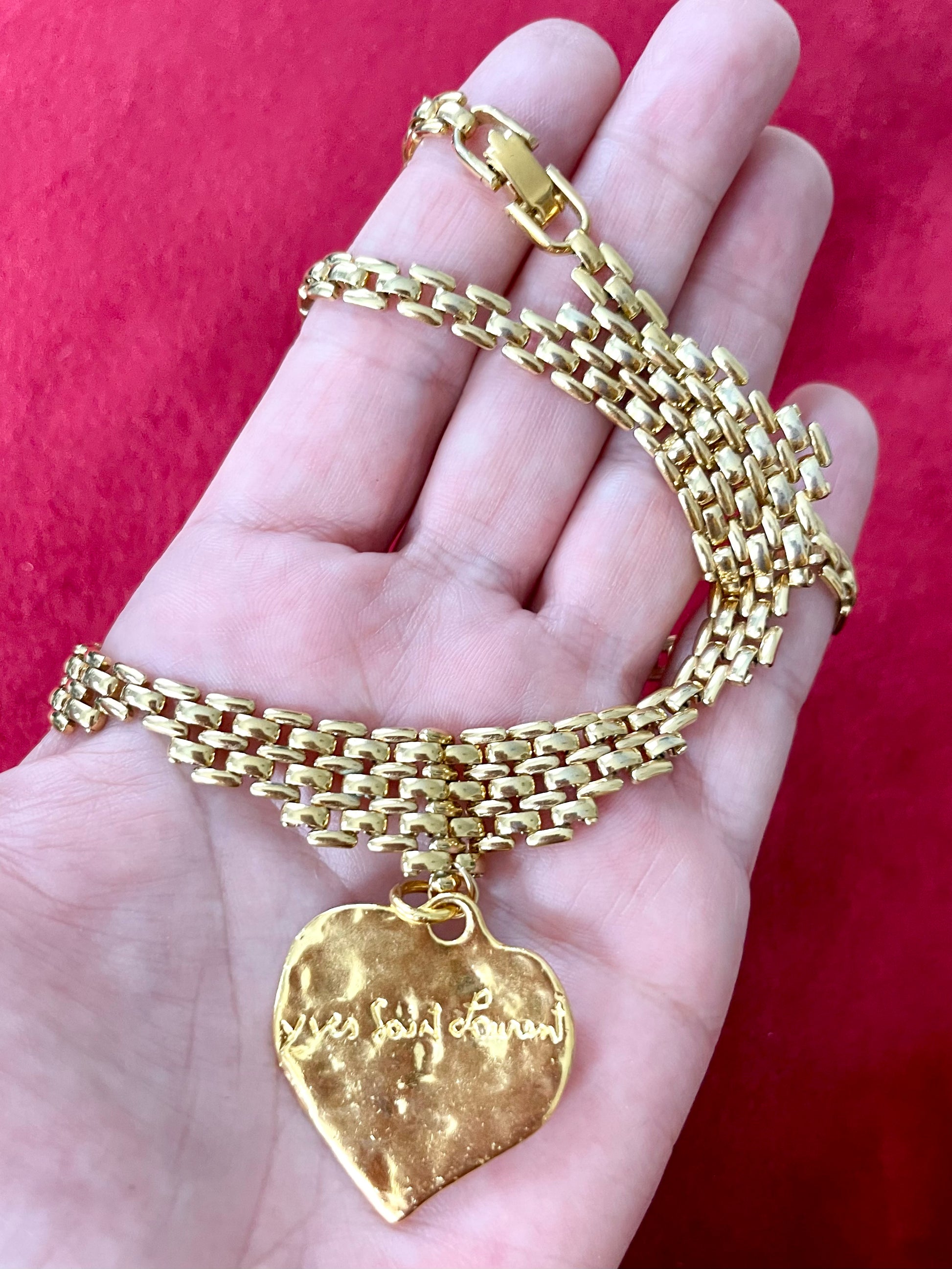 Back side view of Vintage Refurbished 18KG Yves Saint Laurent 80s Love pendant Monet gold necklace , displayed on hand 