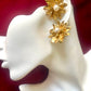 Gold floral vintage Yves Saint Laurent earrings with pearl centers on a white mannequin head against a red background