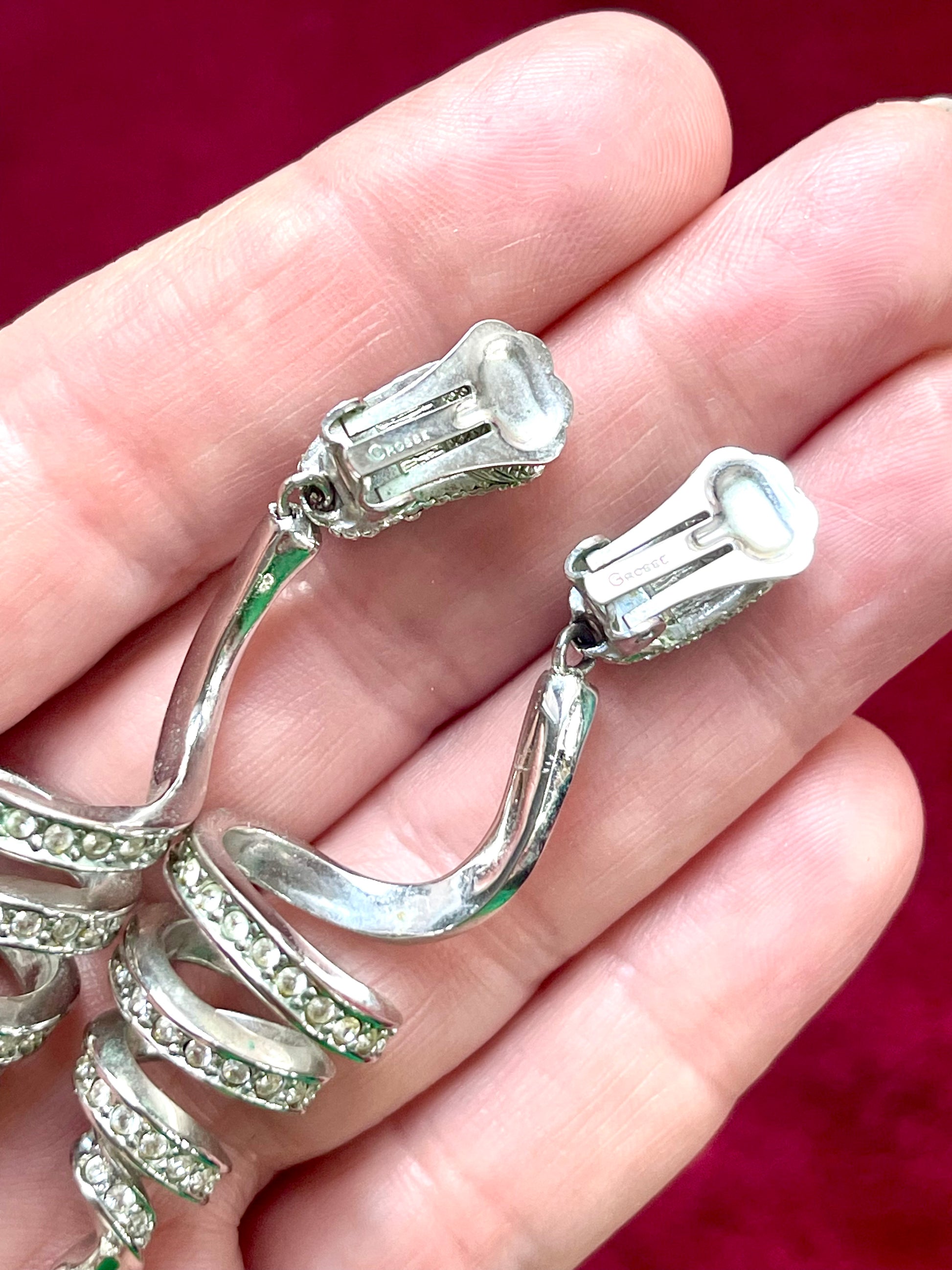 Pair of Grossé rhinestone and pearl drop earrings placed side by side on hand showing the signature 