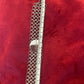 Silver chainmaille Paco Rabanne bracelet with a ruler for scale on a red background
