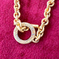 Detailed view of oxidation and patina on vintage Nina Ricci chain holding multiple YSL pendants on red velvet fabric.