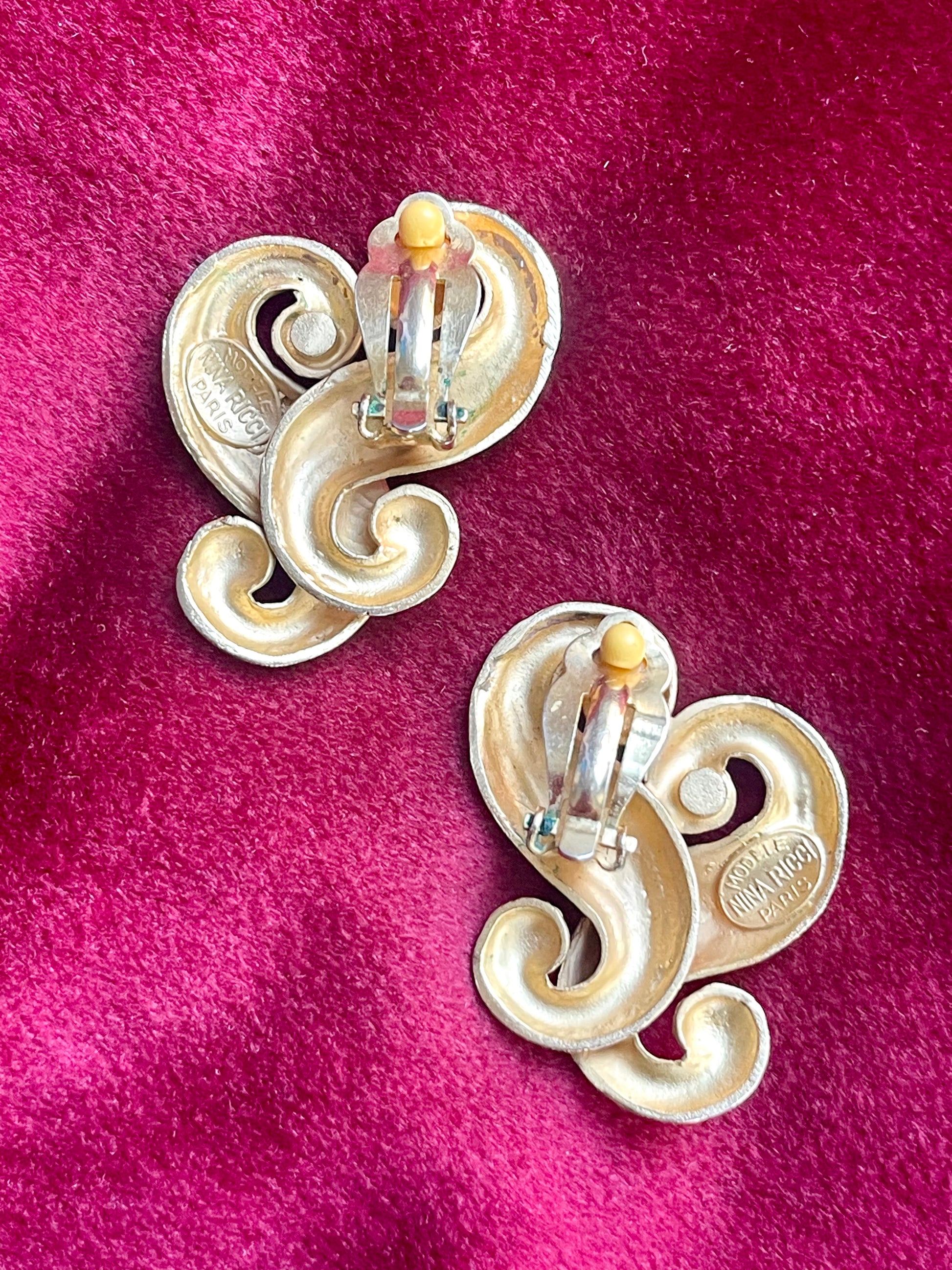Backside view of Vintage Nina Ricci swirly heart earrings in matte gold plated metal, signed Nina Ricci Paris, 1990s design