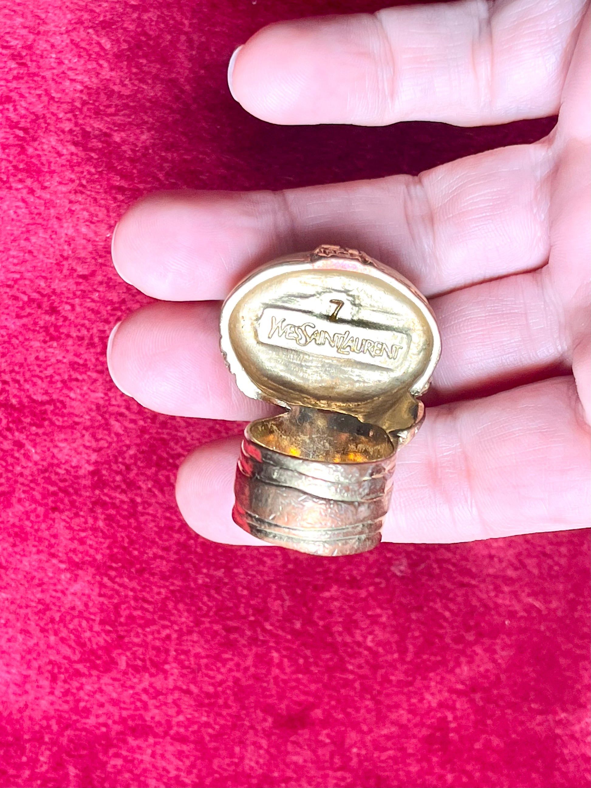 Back of a vintage Yves Saint Laurent ring on hand , showing slight wear on the gold metal band, consistent with its vintage character.authentic signed , size 7
