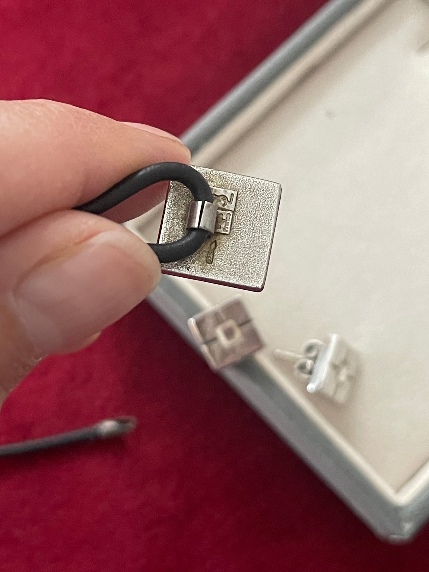 Back side view Vintage Yves Saint Laurent silver 925 earrings and pendant necklace set displayed on hand showing the tag signature of YSL made in France 