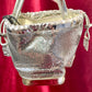 Close up Full view of Paco Rabanne silver shoulder/wrist bag with both straps shown, on red velvet fabric background.