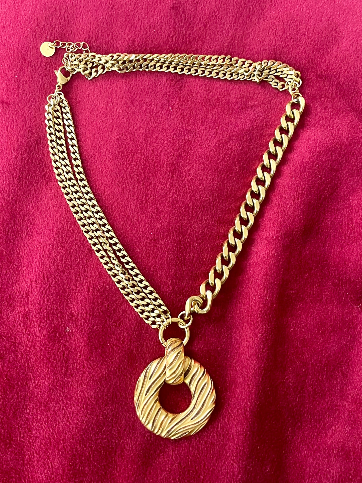 Gold tone Yves Saint Laurent vintage pendant  stainless steel chain necklace on red background 