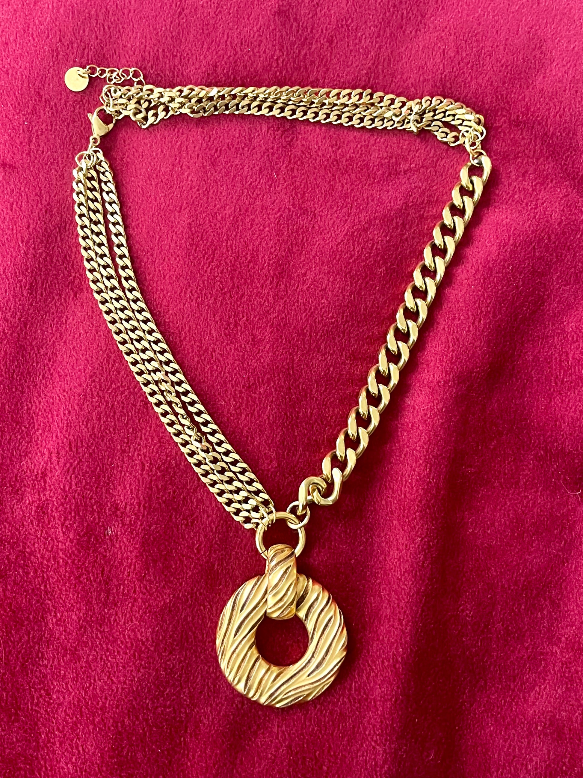 Gold tone Yves Saint Laurent vintage pendant  stainless steel chain necklace on red background 