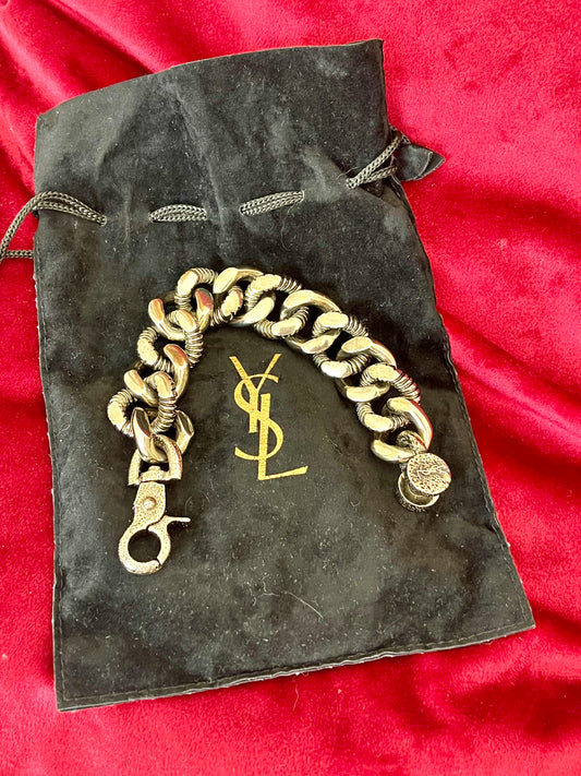 Chunky Yves Saint Laurent bronze and grey chain flat over black clothing, highlighting its unisex modern design