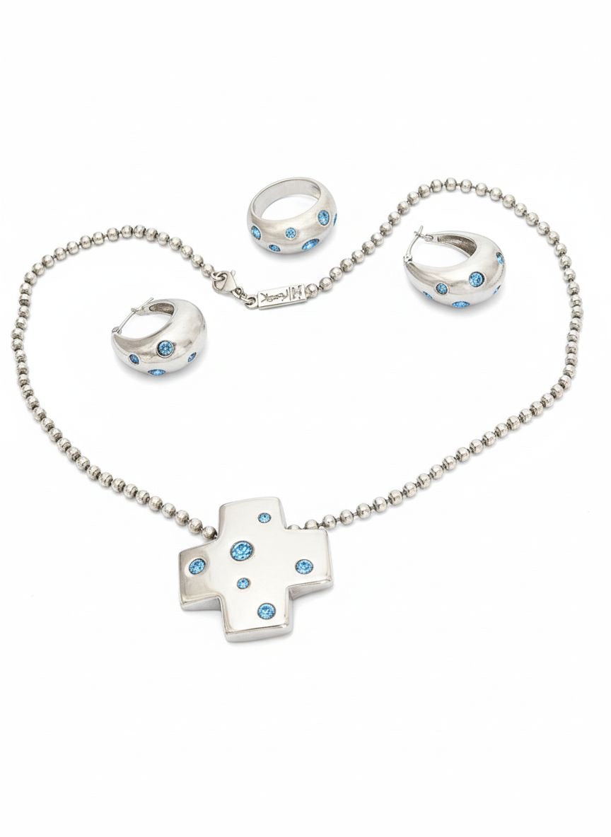 Vintage YSL silver jewelry set displayed on red fabric: silver earrings, cross pendant necklace on beaded chain and ring 