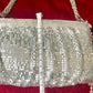 Length measurement of the One of a kind handmade Paco Rabanne repurposed silver pixel mesh bag using a measuring tape on a red background 