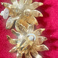 Back side view Vintage Yves Saint Laurent Gold sun-shaped earrings with rhinestones on a pink background showing signature hallmark 