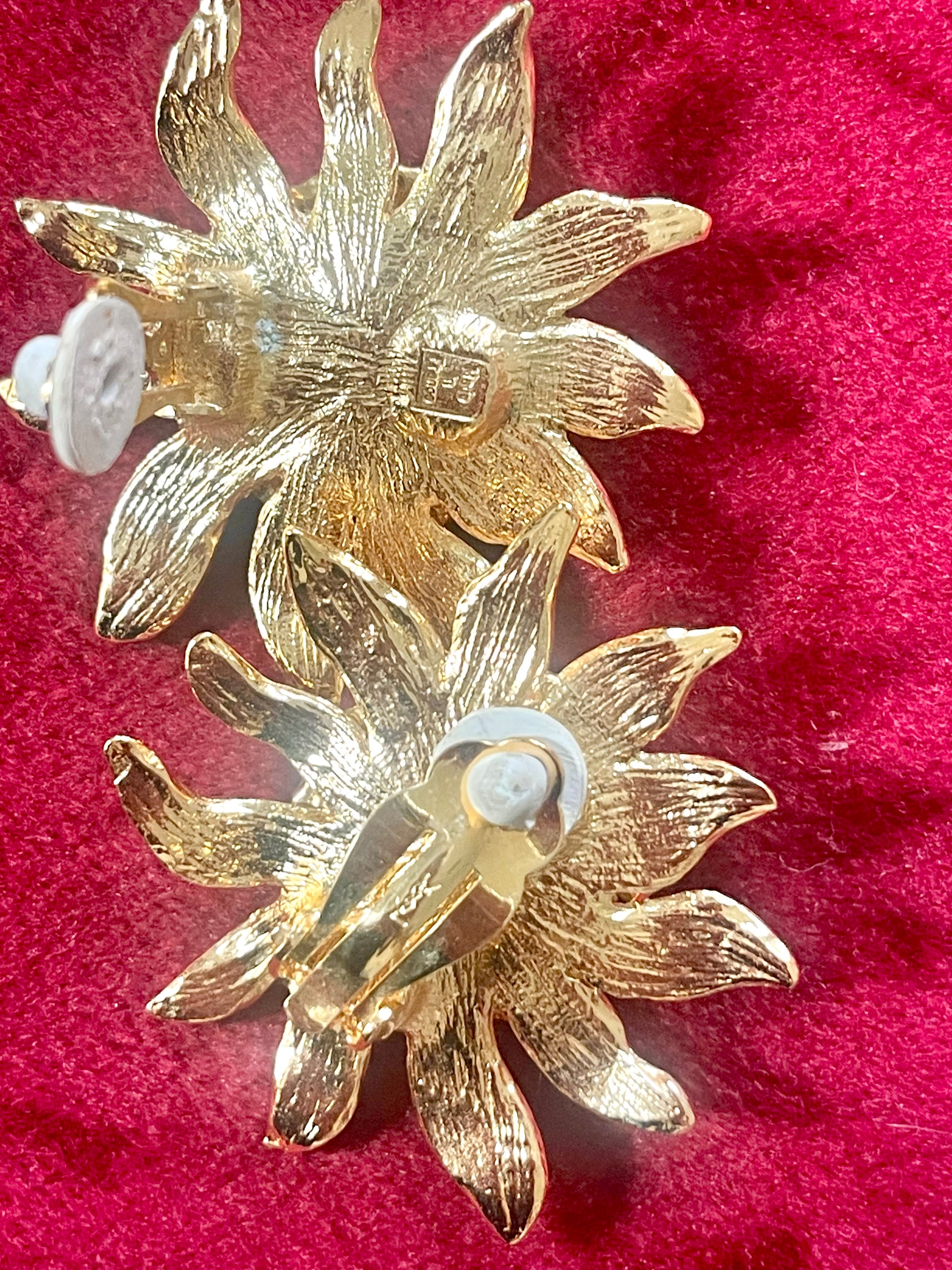 Back side view Vintage Yves Saint Laurent Gold sun-shaped earrings with rhinestones on a pink background showing signature hallmark 