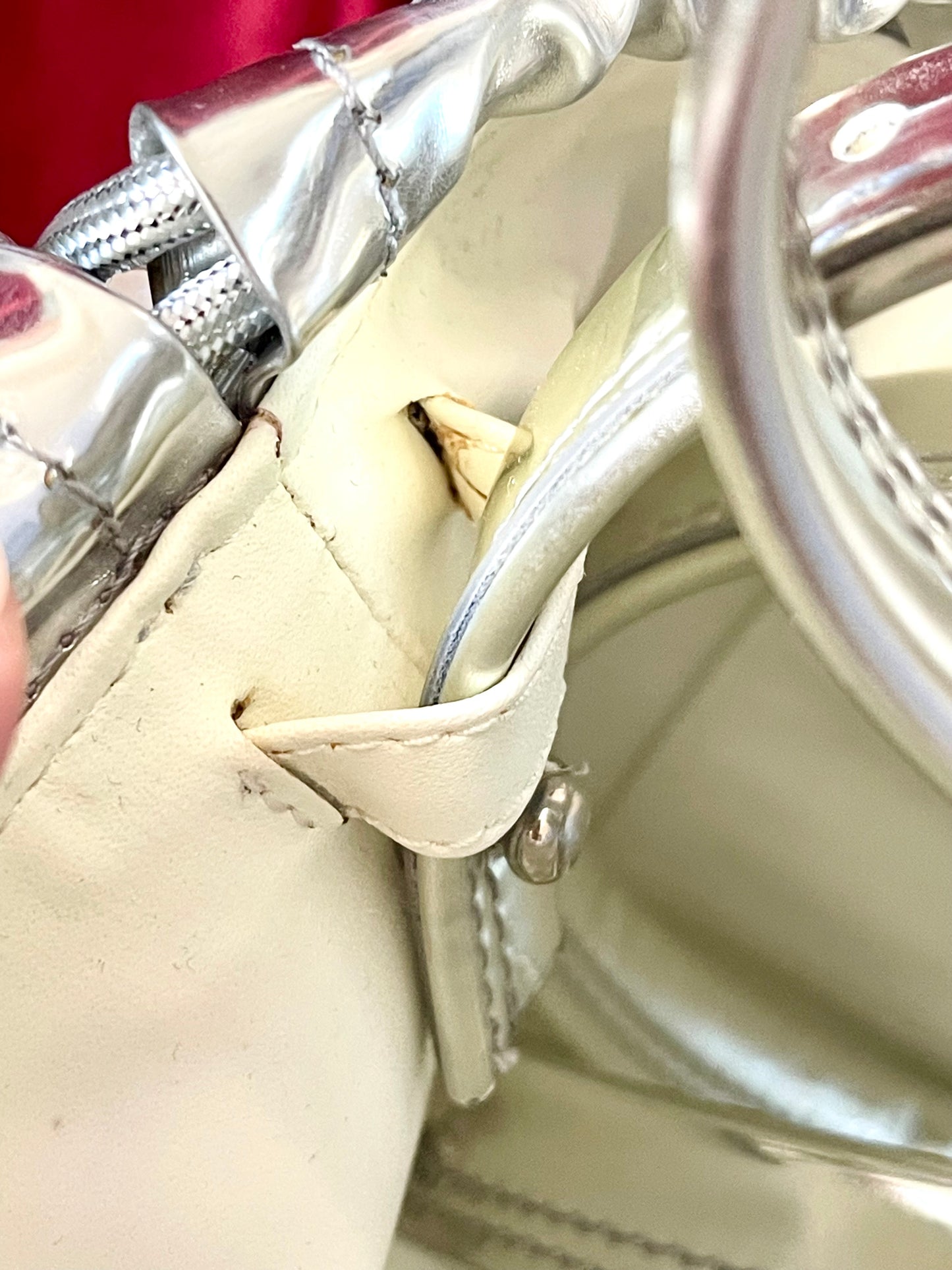 Showing signs of age of Paco Rabanne silver shoulder/wrist bag with both straps shown, on red velvet fabric background.