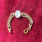 Gold bracelet vintage Yves Saint Laurent with a central gemstone on a red fabric background showing clasp replacement 
