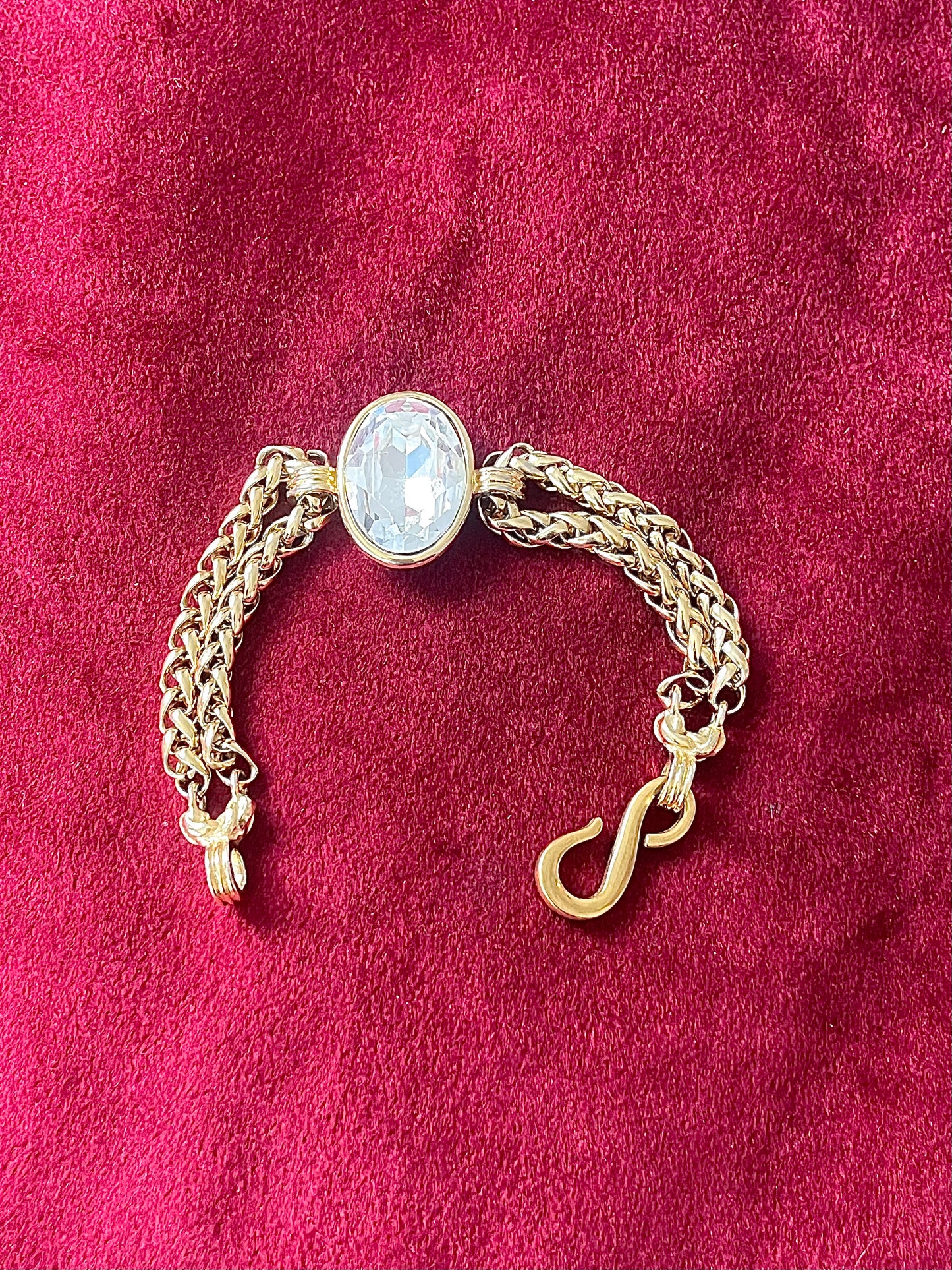 Gold bracelet vintage Yves Saint Laurent with a central gemstone on a red fabric background showing clasp replacement 