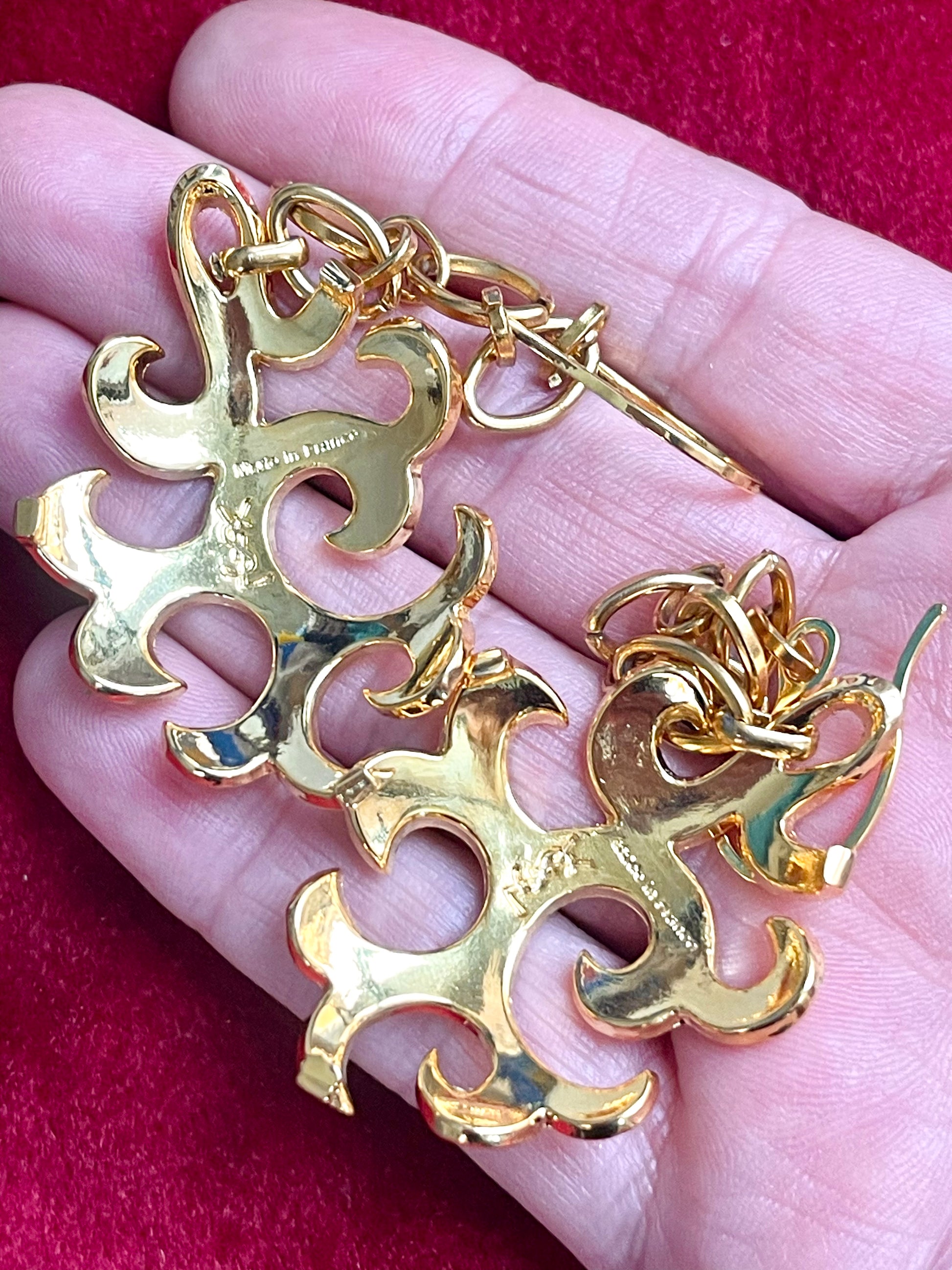 Back view of Yves Saint Laurent vintage earrings showing signature and finish displayed on hand 