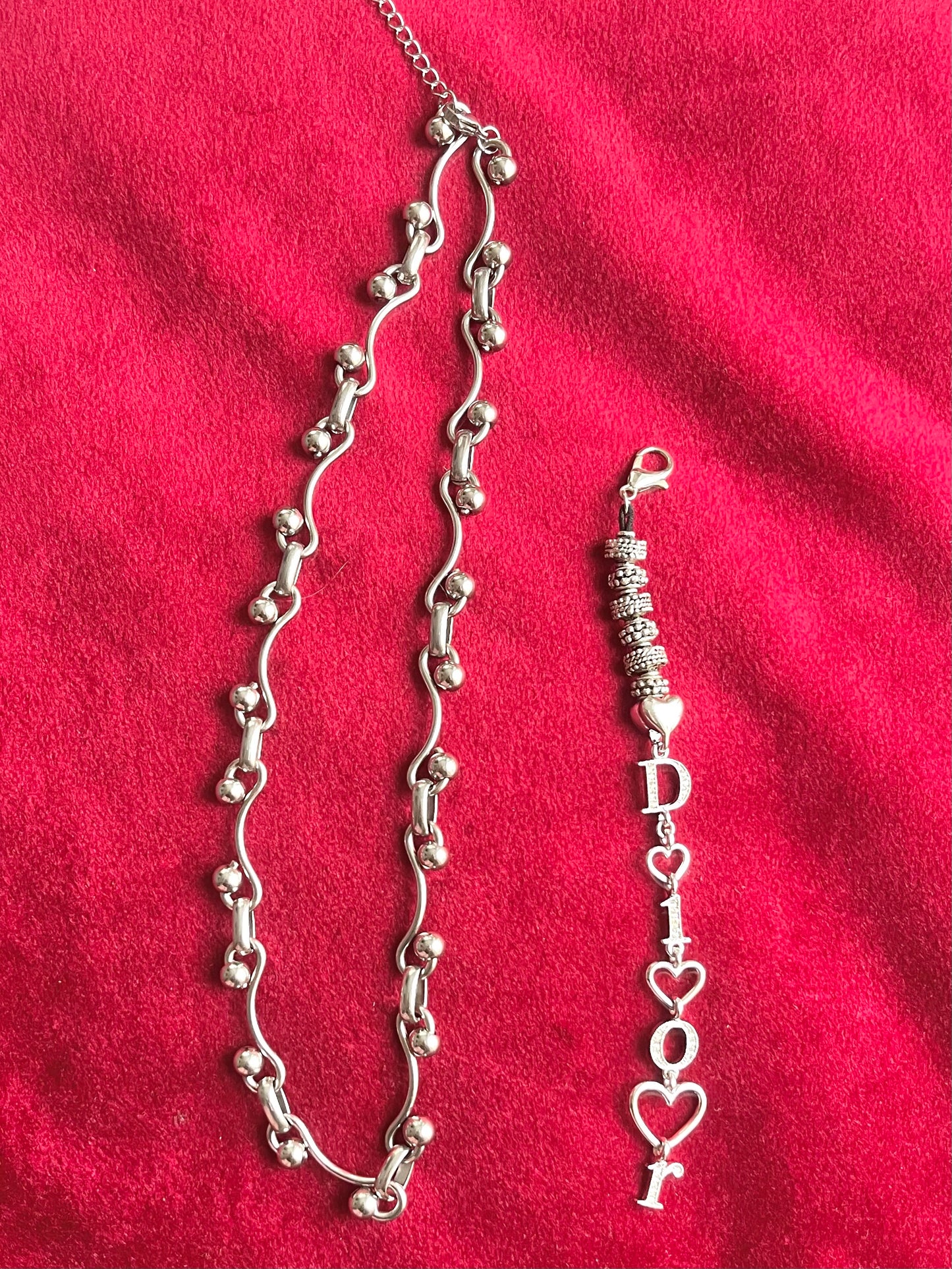 Dior phone charm necklace showing removable clasp and silver beads on red background 