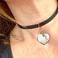 Close up of a Person wearing a black leather Yves Saint Laurent choker necklace with a heart-shaped pendant and logo charm YSL