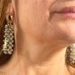 Close up of model wearing Gold and silver earrings with pearl-like beads and YSL Yves Saint Laurent charms