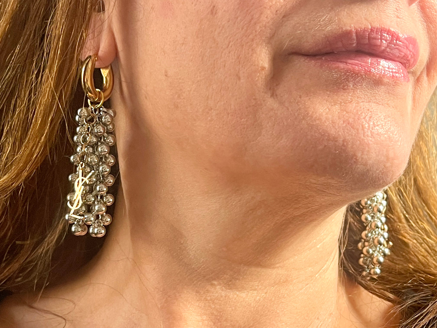 Close up of model wearing Gold and silver earrings with pearl-like beads and YSL Yves Saint Laurent charms