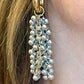 Close up of Gold and silver earrings with pearl-like beads and YSL Yves Saint Laurent charms worn by model