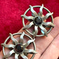 Hand holding a pair of 1980s Paco Rabanne silver-tone sun earrings with dark faceted center stones, highlighting detailing and condition.