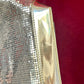 base view of Paco Rabanne silver shoulder/wrist bag with both straps shown, on red velvet fabric background.