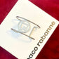 Minimalist vintage Paco Rabanne logo cuff bracelet silver tone On white and red background 