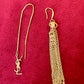 Gold Yves Saint Laurent earrings with chain tassel on a red background