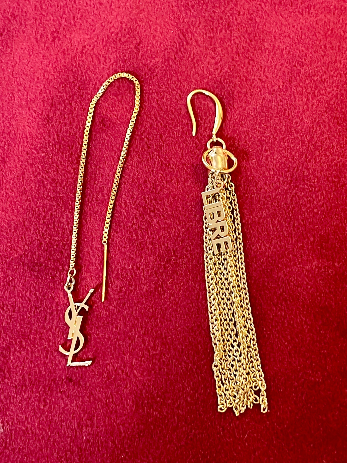 Gold Yves Saint Laurent earrings with chain tassel on a red background