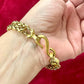 Yves Saint Laurent vintage gold bracelet with a unique clasp on a hand against a red background