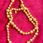 Vintage Yves Saint Laurent gold beaded necklace with textured graduated beads displayed on red velvet background showing tag