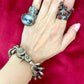 Worn by model Top view Preloved YSL bronze and grey chain worn as a statement piece with arty Yves Saint Laurent rings on a red velvet background 