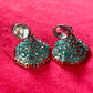 Close-up of Yves Saint Laurent Rive Gauche vintage statement earrings with turquoise and red rhinestones against a red velvet background.