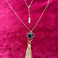 Gold-plated necklace from Mutton Collet with YSL tassel charm and branded chain tag shown on red velvet fabric