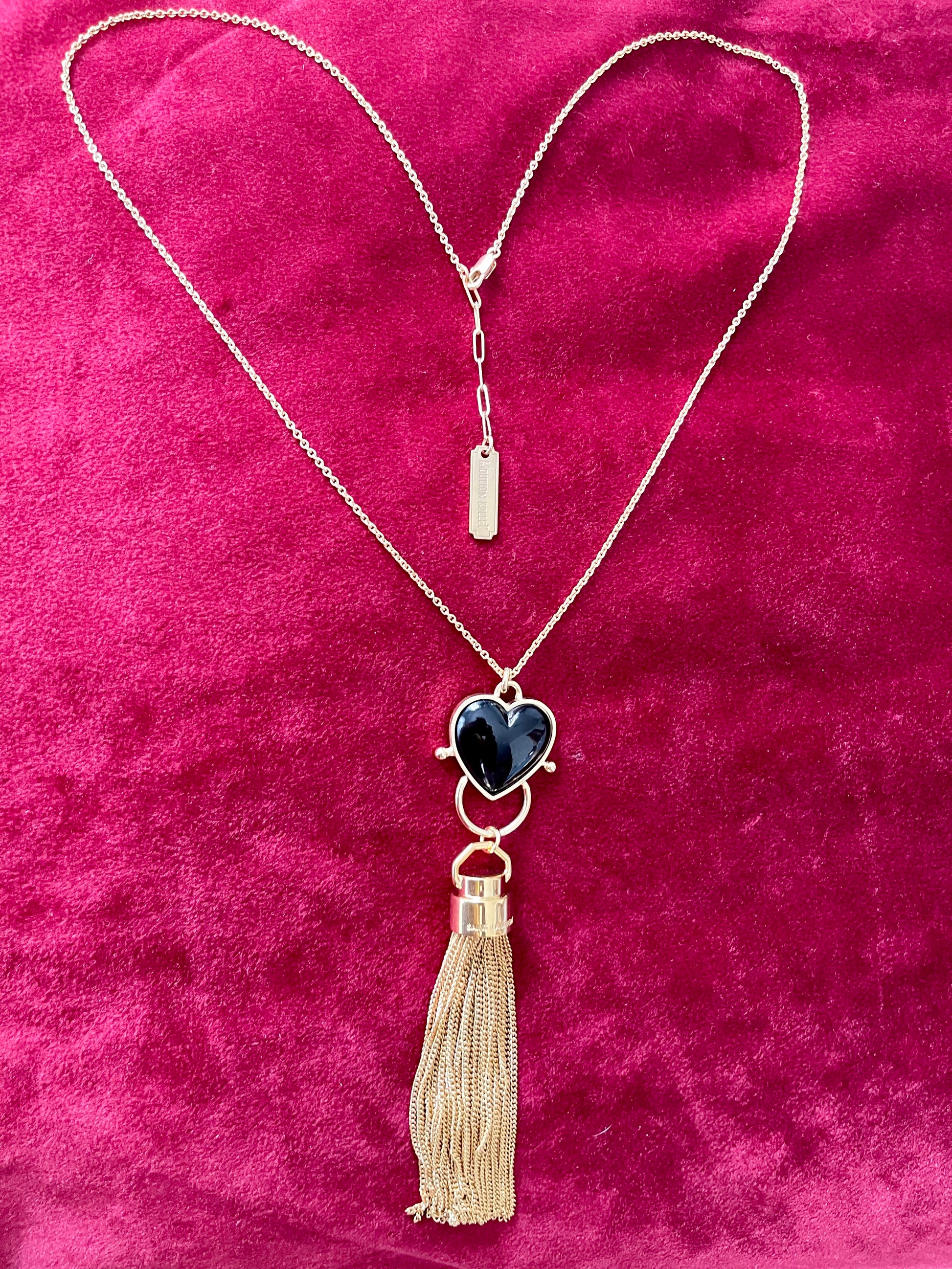 Gold-plated necklace from Mutton Collet with YSL tassel charm and branded chain tag shown on red velvet fabric