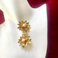Vintage 80s YSL Gold floral earrings with pearl centers on a white and red fabric background