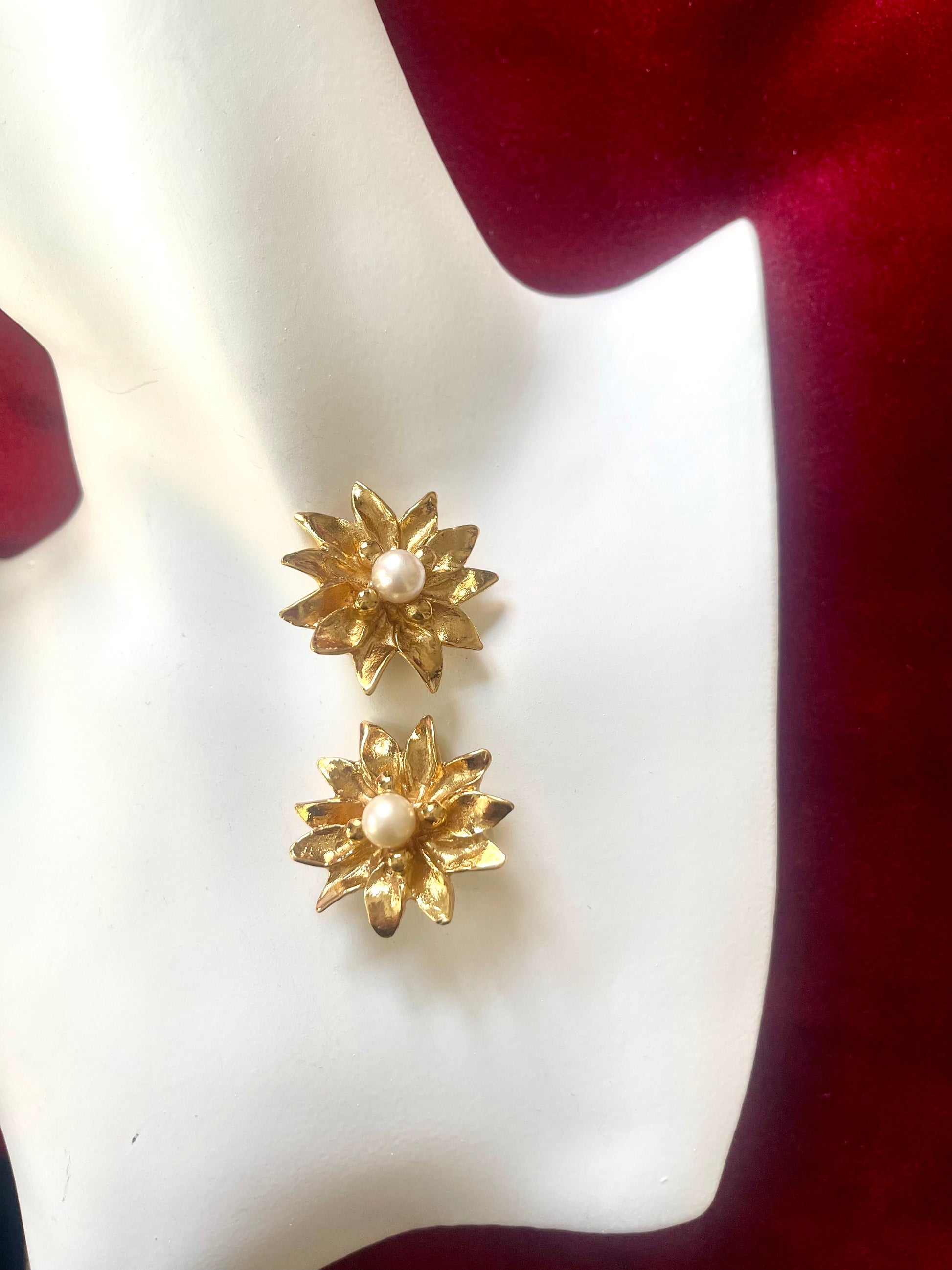 Vintage 80s YSL Gold floral earrings with pearl centers on a white and red fabric background