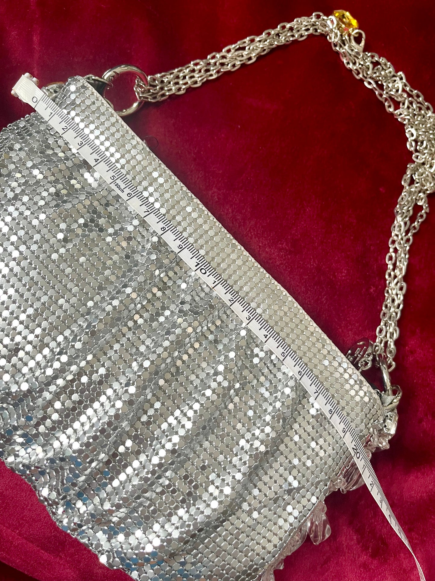 Width measurement of the One of a kind handmade Paco Rabanne repurposed silver pixel mesh bag using a measuring tape on red background 